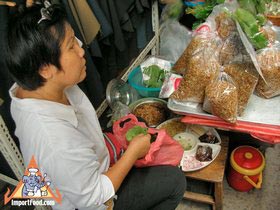 Bangkok Street Vendor Prepares Miang Kham on a Busy Pathway in the Fabric District